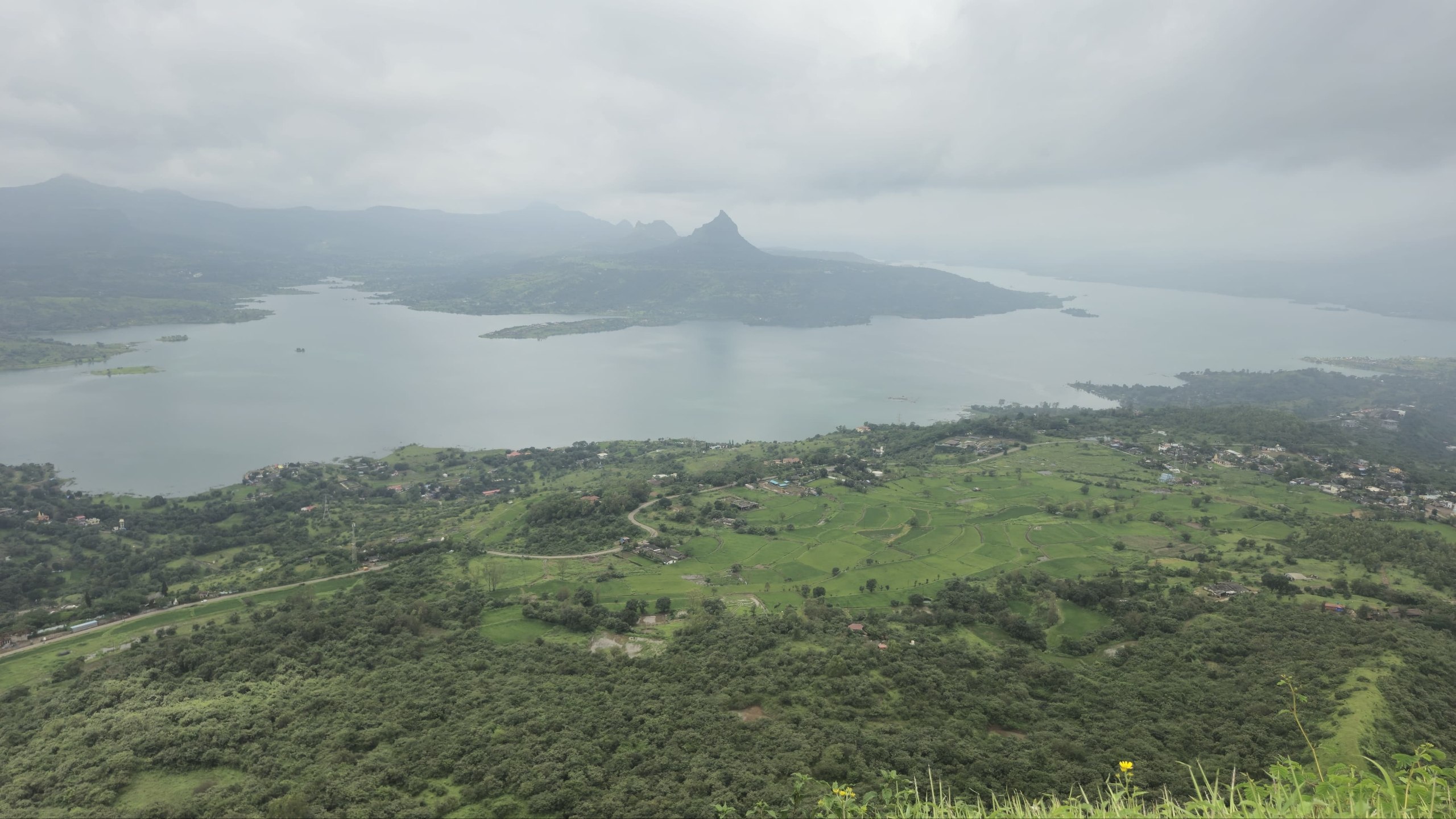 Pawna Lake and the Tung–Lohagad ridges seen from the top of Tikona — the view everyone climbs for.