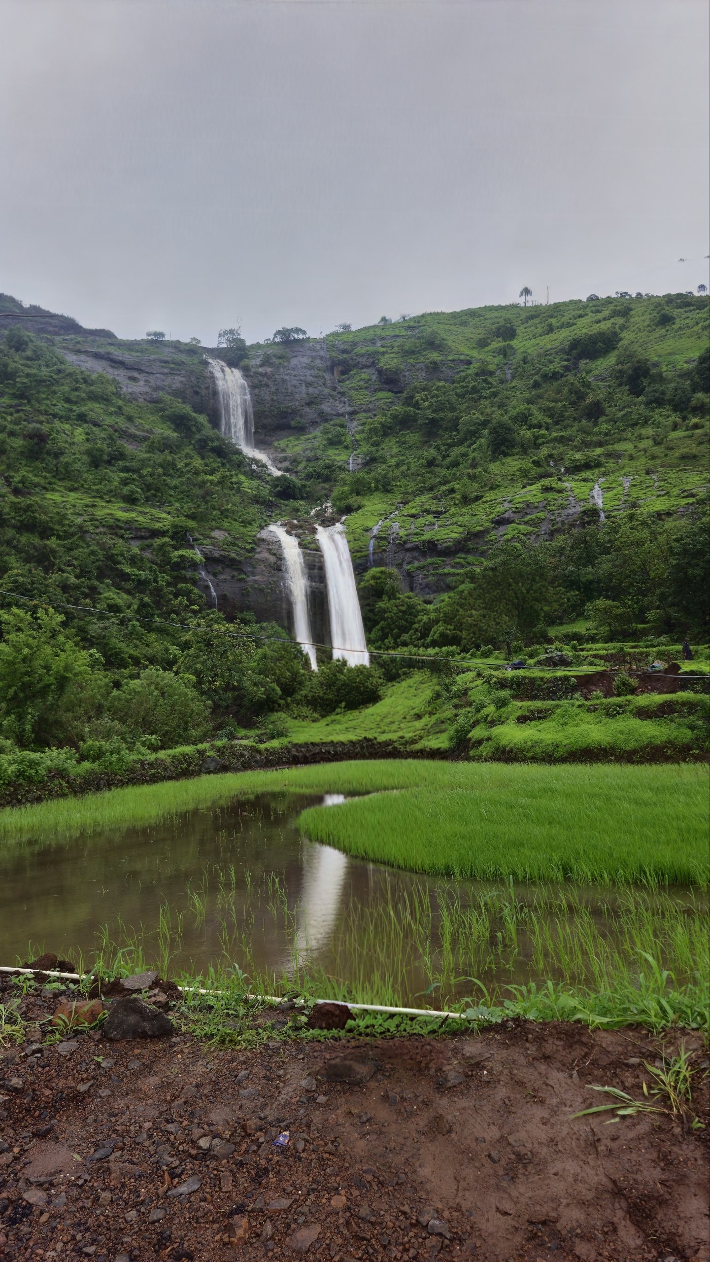 A hidden two-tier waterfall on the Kanhe–Khandi monsoon route, dropping into flooded paddy terraces that mirror the fall.